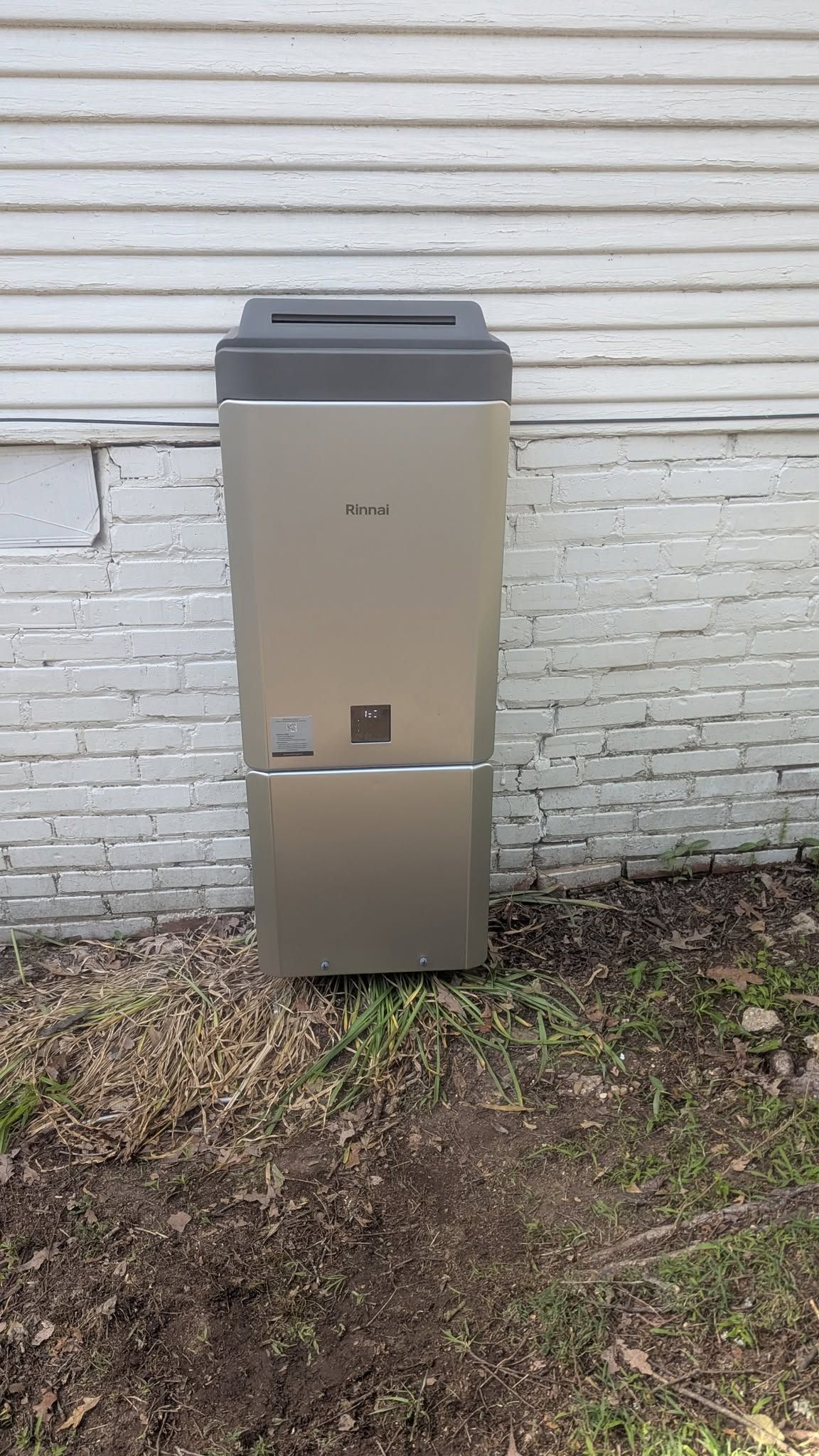 Tall beige utility cabinet against a white brick wall outdoors