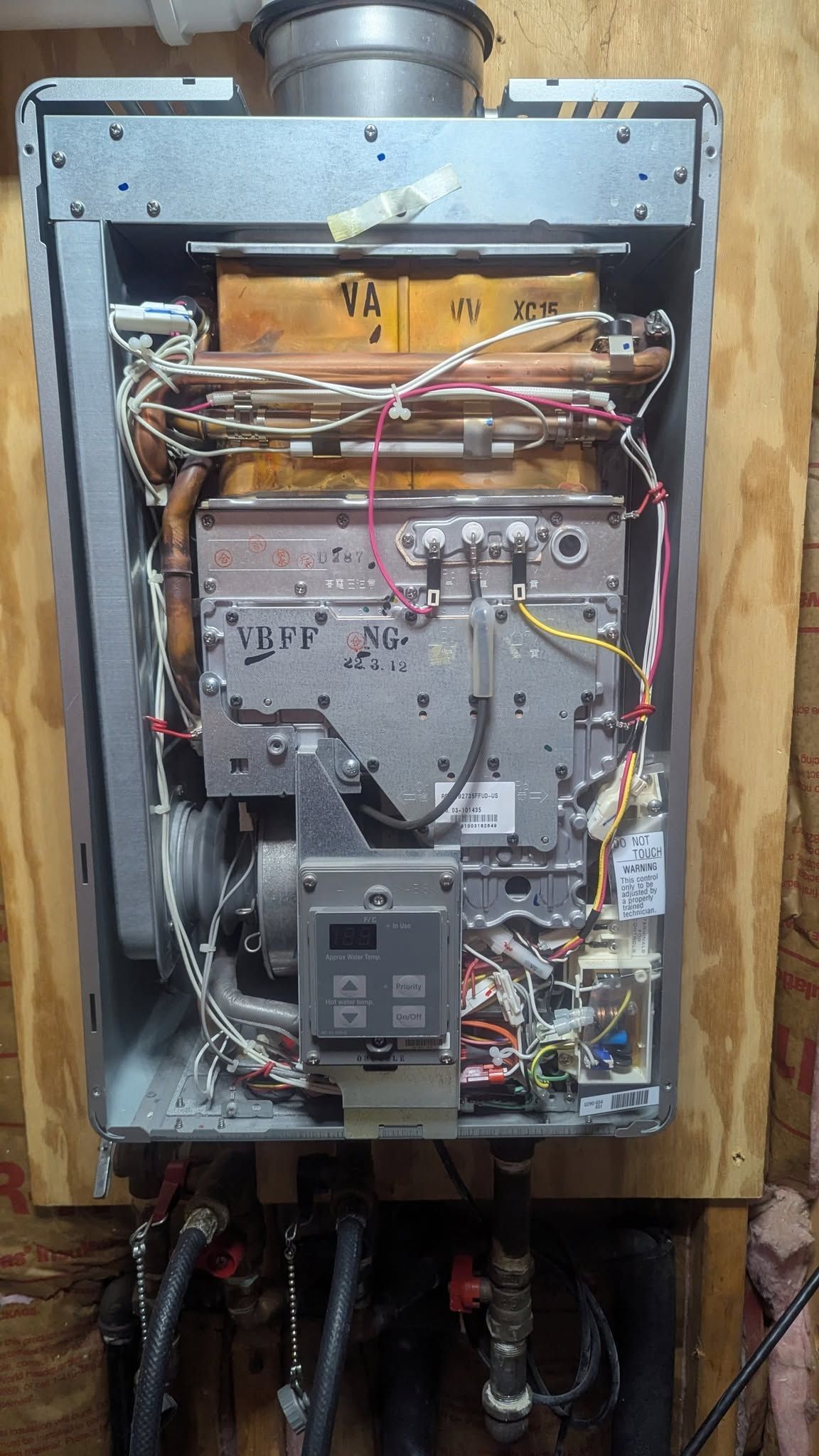 Open electrical furnace panel with exposed wiring, circuit board, and ductwork inside a wooden wall frame