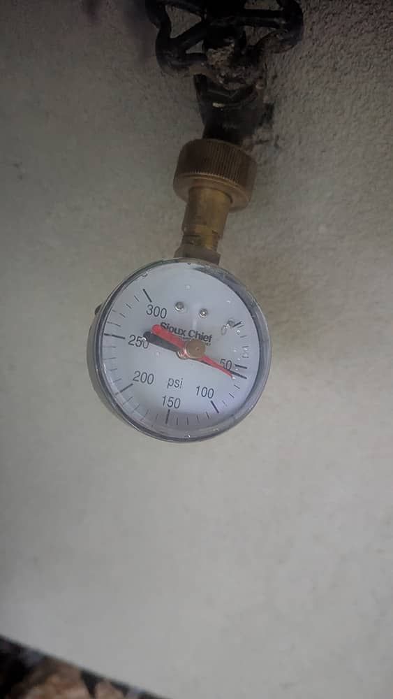 Pressure gauge with a needle pointing near 20 PSI, connected to a brass fitting and valve.