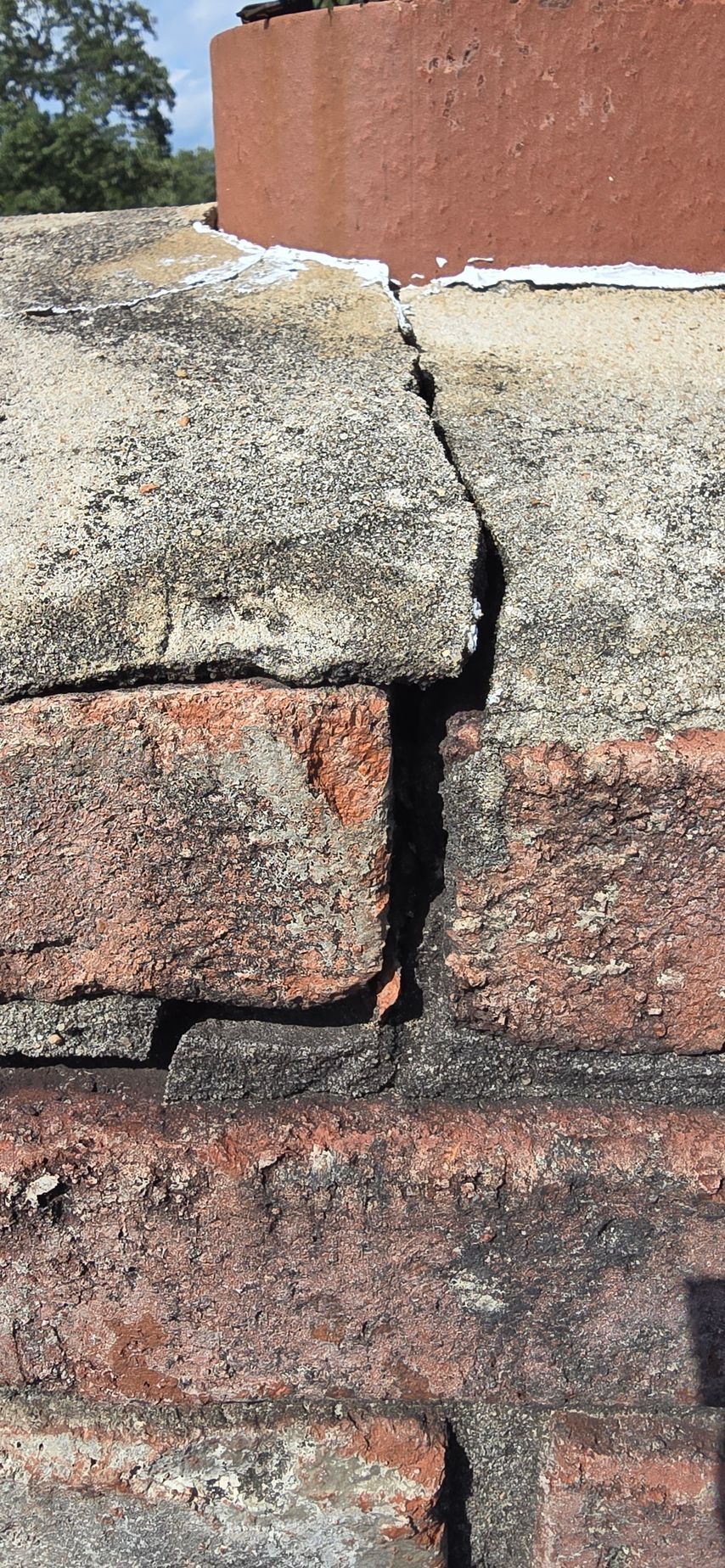 Close-up of a cracked stone wall with a vertical split between tan and reddish bricks.