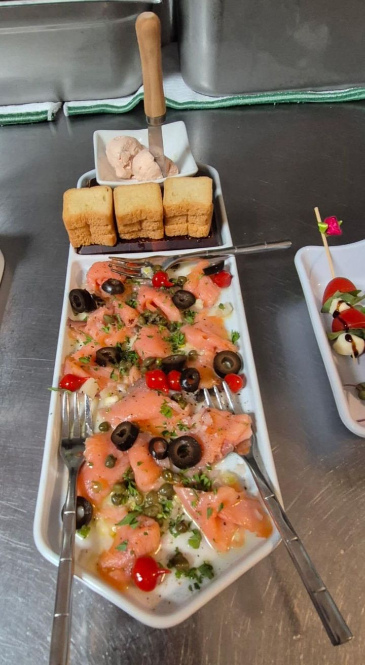 Plate of salmon carpaccio, olives, and capers with toast, dip and a caprese skewer.