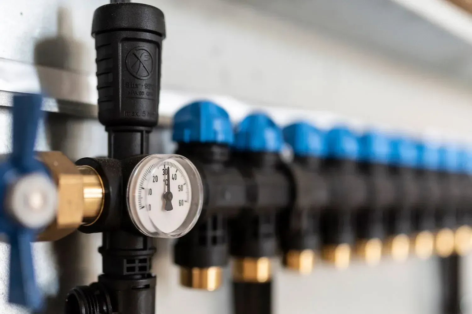 Row of black pipes with blue caps, a pressure gauge, and brass fittings.
