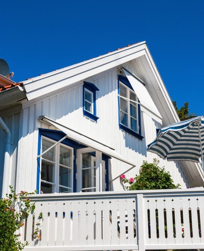 A White House with Blue Trim and A Striped Awning — Rearden Fencing Pty Ltd in Toronto, NSW
