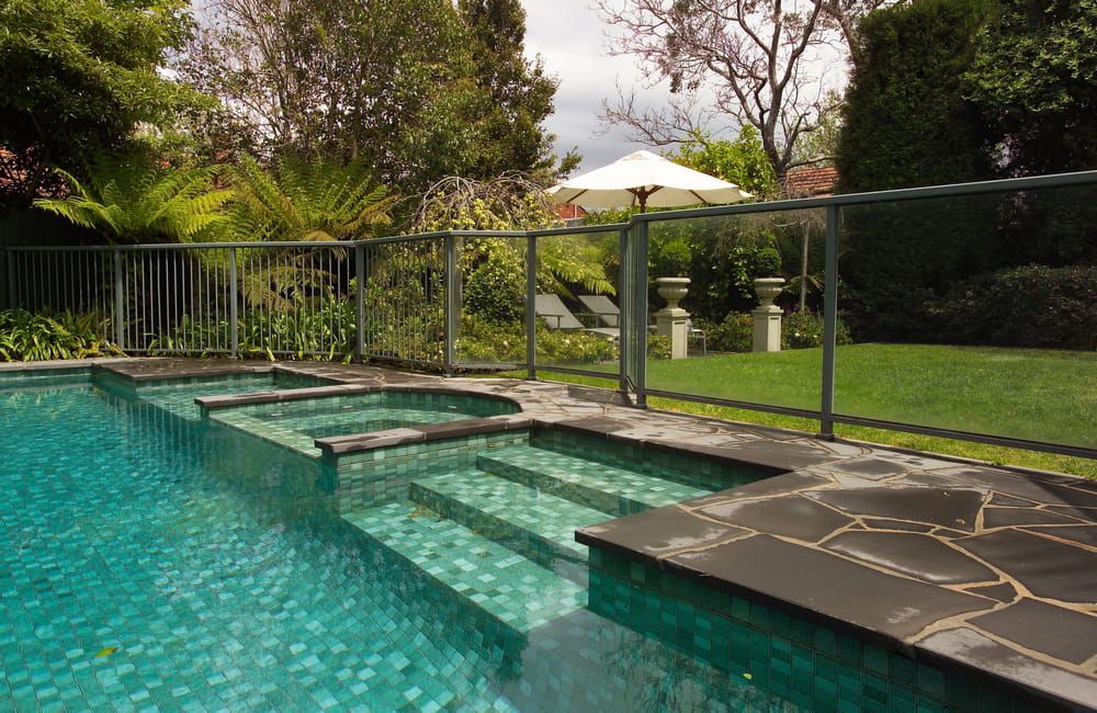 A Large Swimming Pool with Stairs and A Fence Around It — Rearden Fencing Pty Ltd in Toronto, NSW