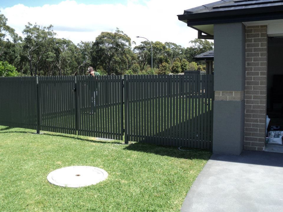 A Fence Surrounds a Lush Green Yard in Front of A House — Rearden Fencing Pty Ltd in West Lakes, SA