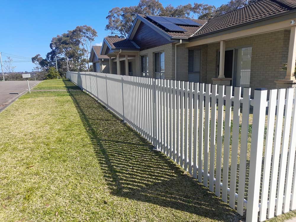 A White Picket Fence Surrounds a Row of Houses — Rearden Fencing Pty Ltd in Toronto, NSW