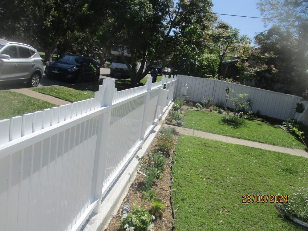 A White Fence Surrounds a Lush Green Yard — Rearden Fencing Pty Ltd in Toronto, NSW