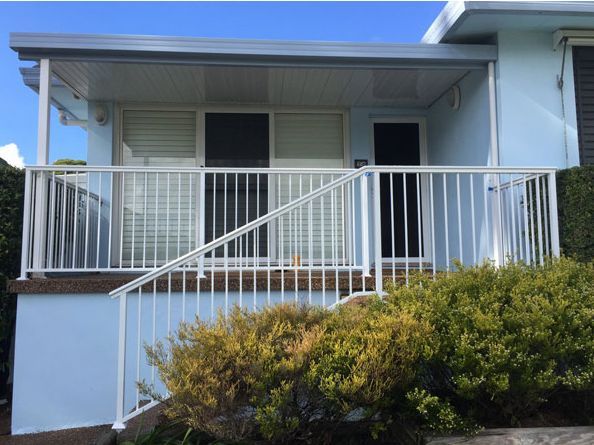 A Blue House With a White Railing and Stairs Leading Up to It — Rearden Fencing Pty Ltd in Toronto, NSW
