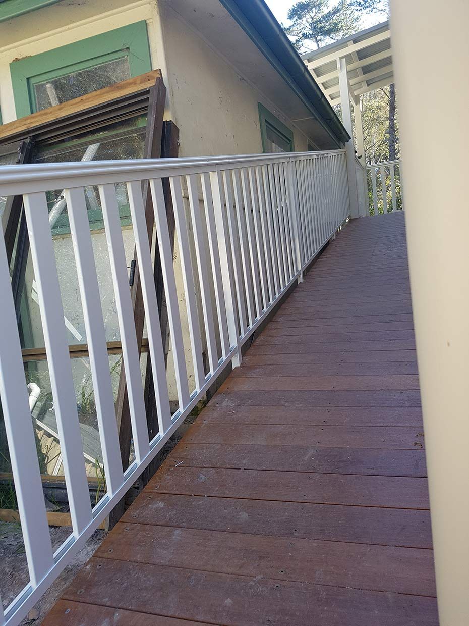 A Wooden Ramp With a White Railing Leading to a House — Rearden Fencing Pty Ltd in Toronto, NSW