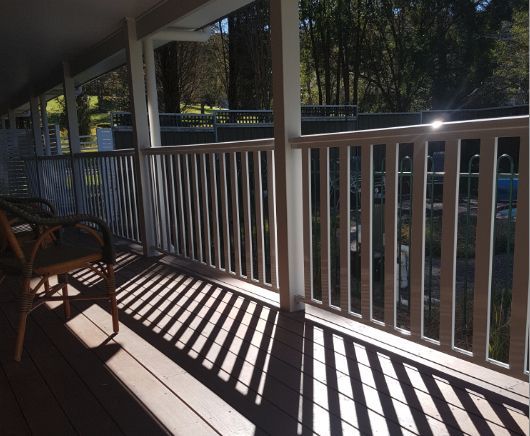 A Porch With a White Railing and a Rocking Chair — Rearden Fencing Pty Ltd in Toronto, NSW
