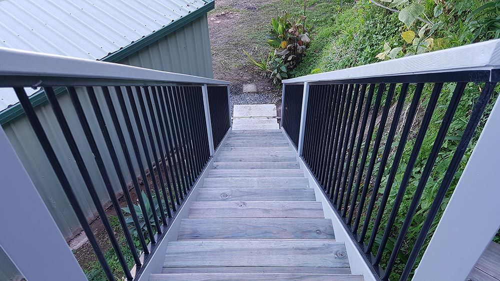 A Wooden Staircase With a Metal Railing Leading Up to a House — Rearden Fencing Pty Ltd in Toronto, NSW