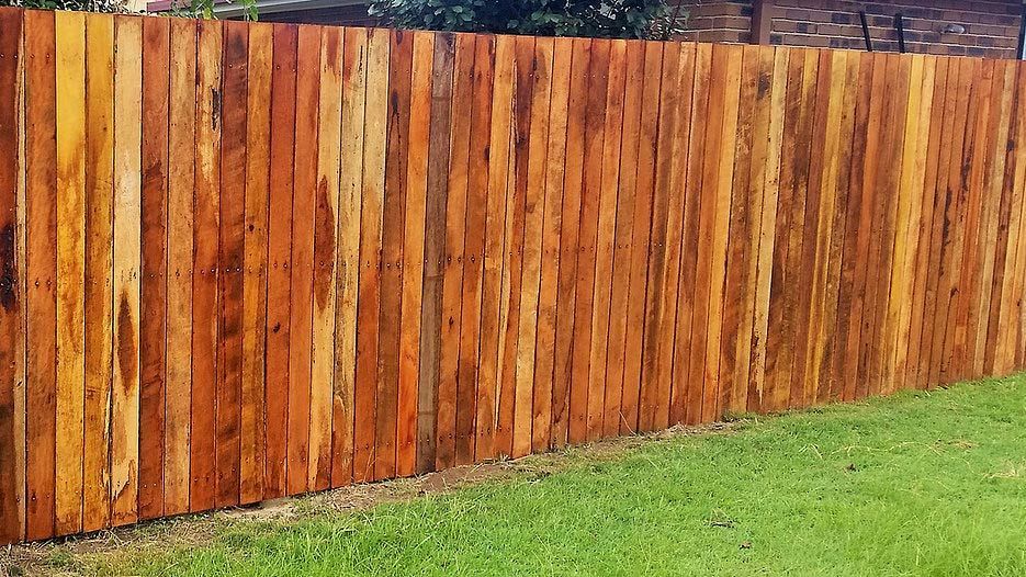 A Wooden Fence is Sitting on Top of a Lush Green Lawn — Rearden Fencing Pty Ltd in Toronto, NSW