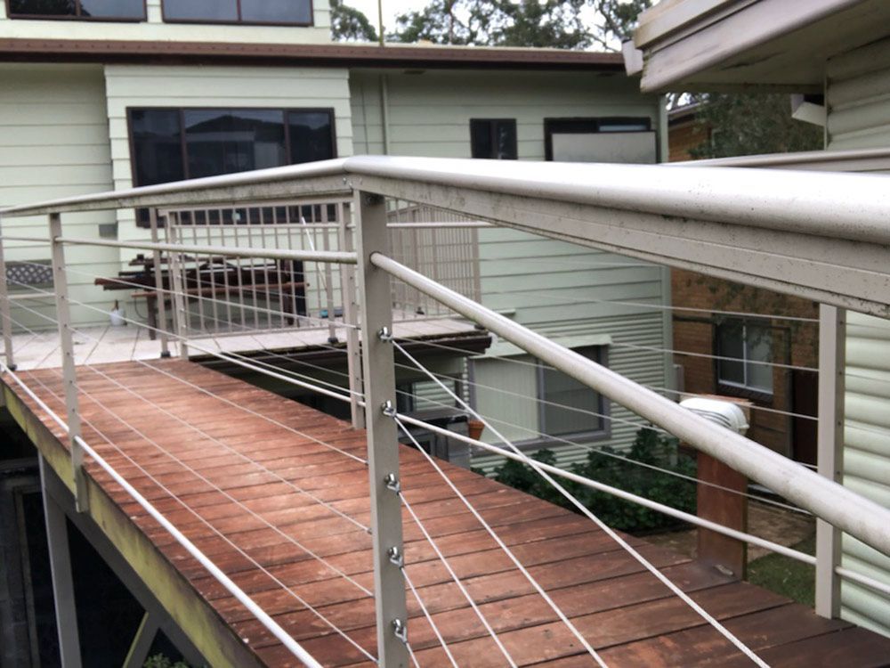 A Balcony With a Stainless Steel Railing and a Wooden Deck — Rearden Fencing Pty Ltd in Toronto, NSW