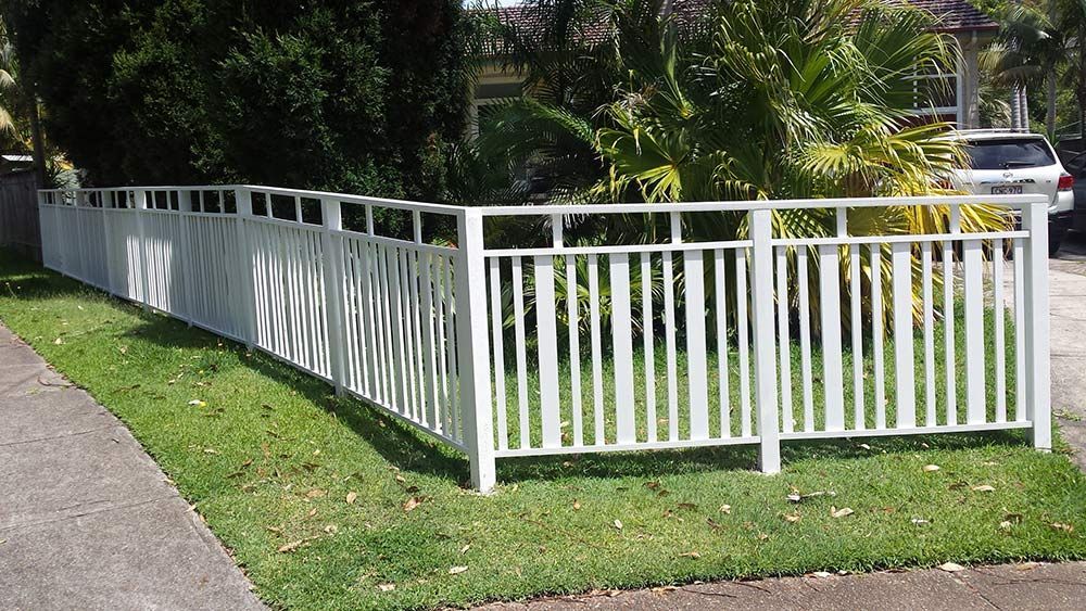 A White Fence Surrounds a Lush Green Yard — Rearden Fencing Pty Ltd in Toronto, NSW