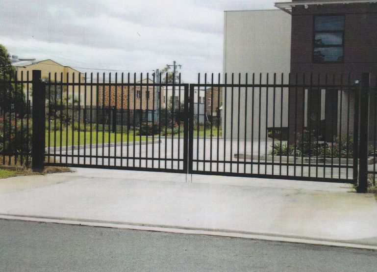 A Black Fence Surrounds a Driveway in Front of a House — Rearden Fencing Pty Ltd in Toronto, NSW
