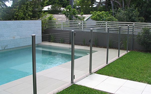 A Swimming Pool With a Glass Fence Around It — Rearden Fencing Pty Ltd in Toronto, NSW