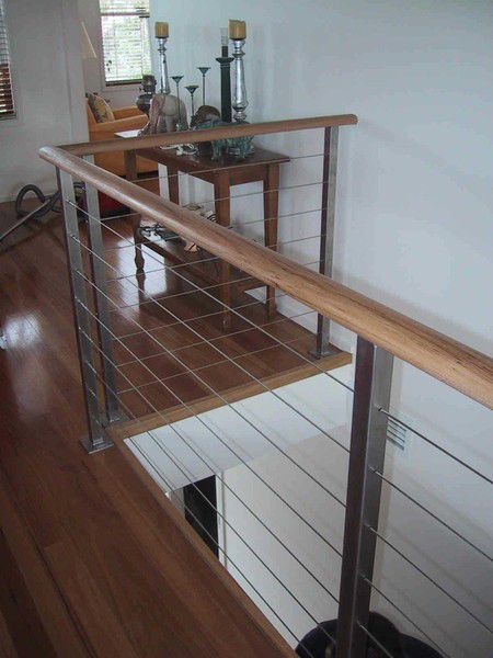 A Stainless Steel Railing With a Wooden Handrail in a Living Room — Rearden Fencing Pty Ltd in Toronto, NSW