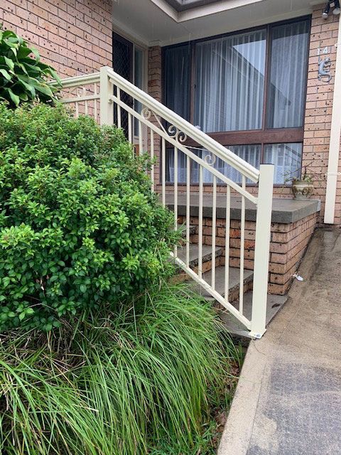 A Brick House With a White Railing and Stairs Leading Up to It — Rearden Fencing Pty Ltd in Toronto, NSW