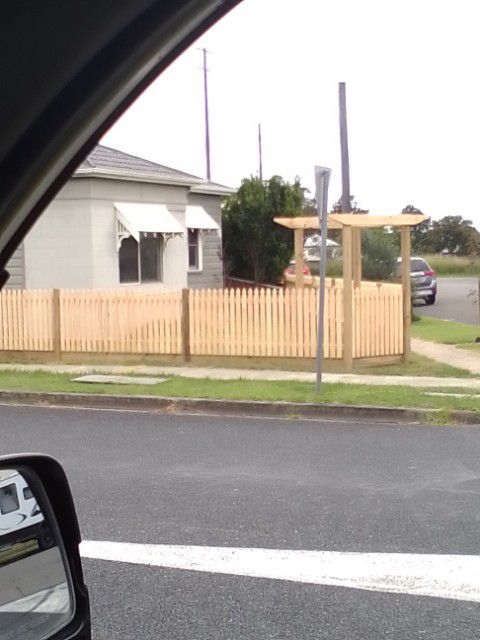 A Car is Driving Down a Street With a Wooden Fence — Rearden Fencing Pty Ltd in Toronto, NSW
