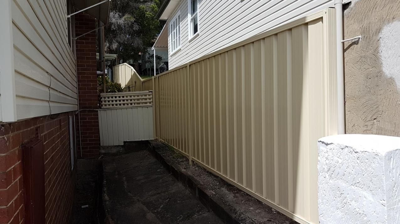 A Narrow Alleyway Between Two Houses with A White Fence — Rearden Fencing Pty Ltd in Toronto, NSW