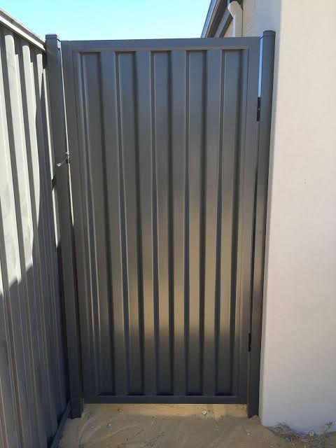 A Black Metal Gate is Sitting Next to a Fence — Rearden Fencing Pty Ltd in Toronto, NSW