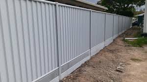 A White Fence is Sitting on Top of a Dirt Road Next to a House — Rearden Fencing Pty Ltd in Toronto, NSW