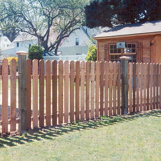 A Wooden Picket Fence Surrounds a Lush Green Yard in Front of a Shed — Rearden Fencing Pty Ltd in Toronto, NSW