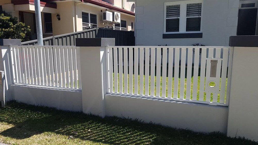 A White Fence is in Front of a House — Rearden Fencing Pty Ltd in Toronto, NSW