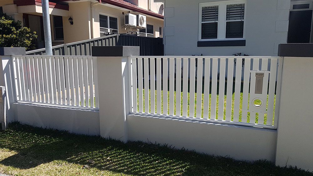 A White Fence is in Front of a House — Rearden Fencing Pty Ltd in Toronto, NSW