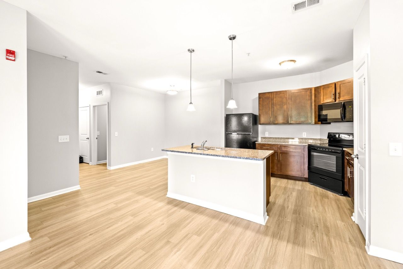 Open-concept kitchen and living area with an island, granite countertop, and dark wood cabinets.
