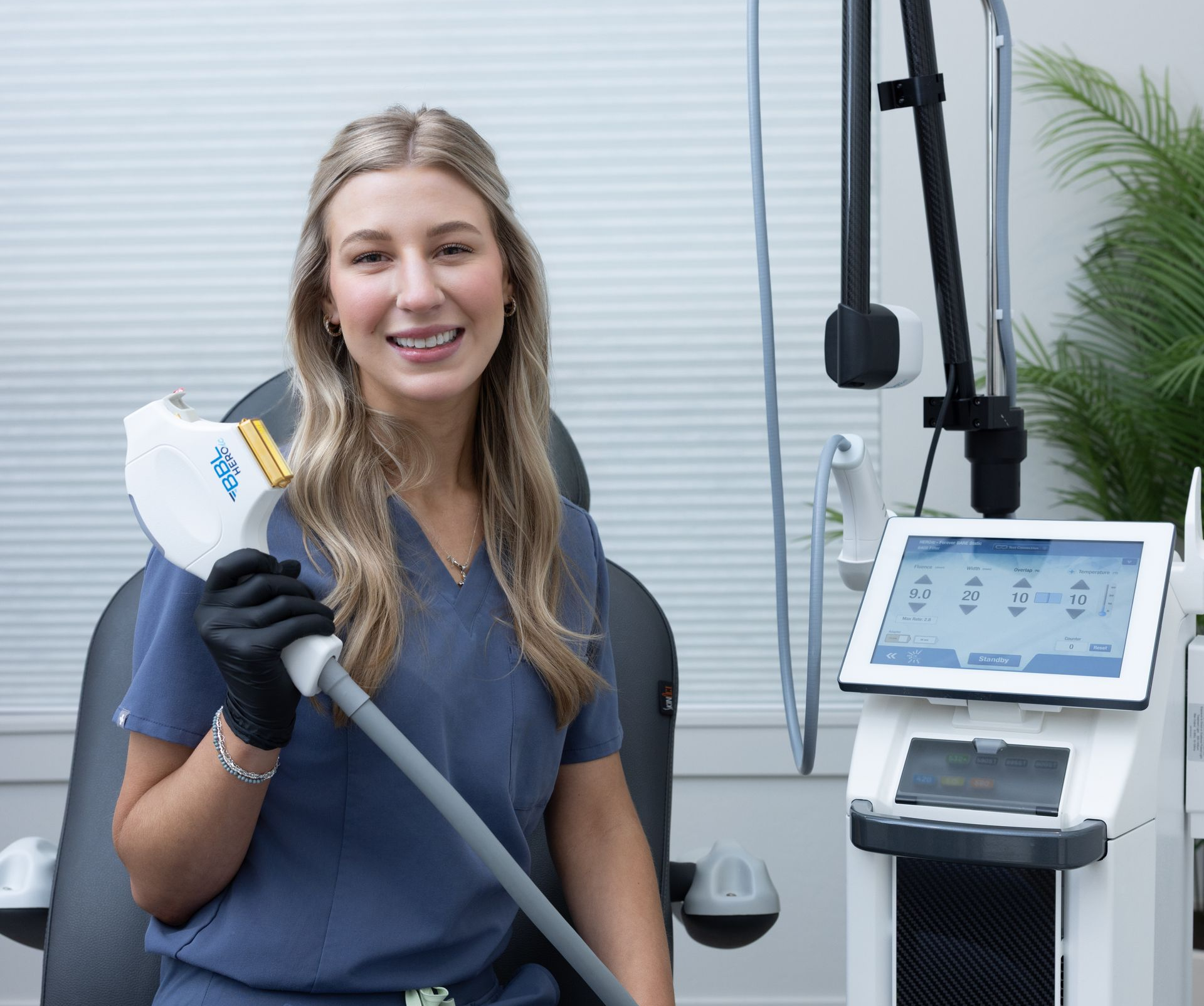 Woman in a dental clinic holding an oral device beside a medical monitor