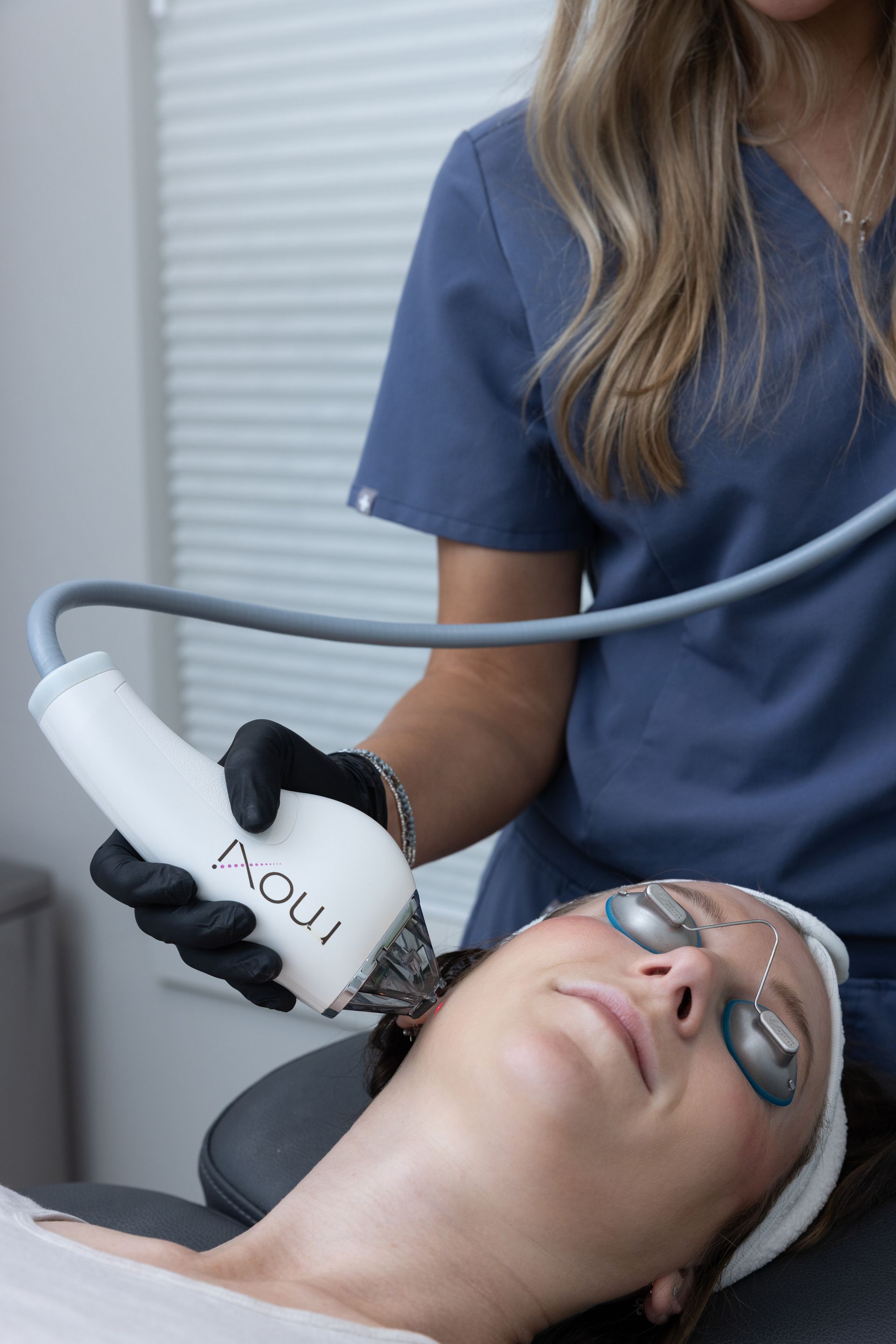 A person receiving a facial treatment with a handheld device in a spa setting