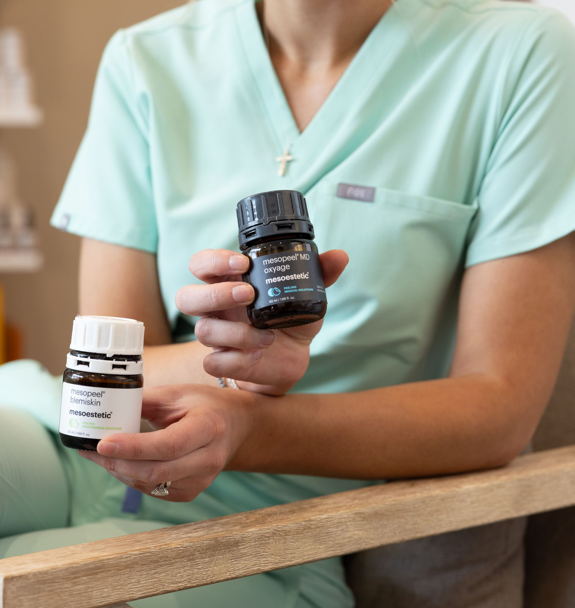 Aesthetician applying treatment to a client’s face in a spa room, with a towel and teal gloves.