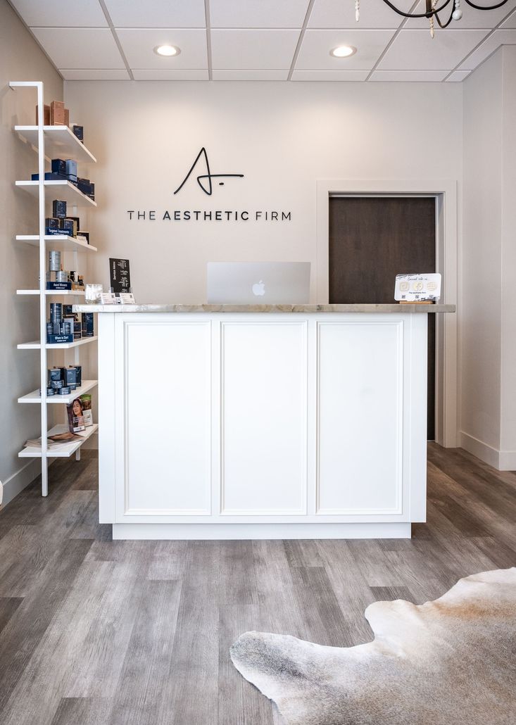 Bright reception desk in a modern white office lobby with shelves and a logo on the wall