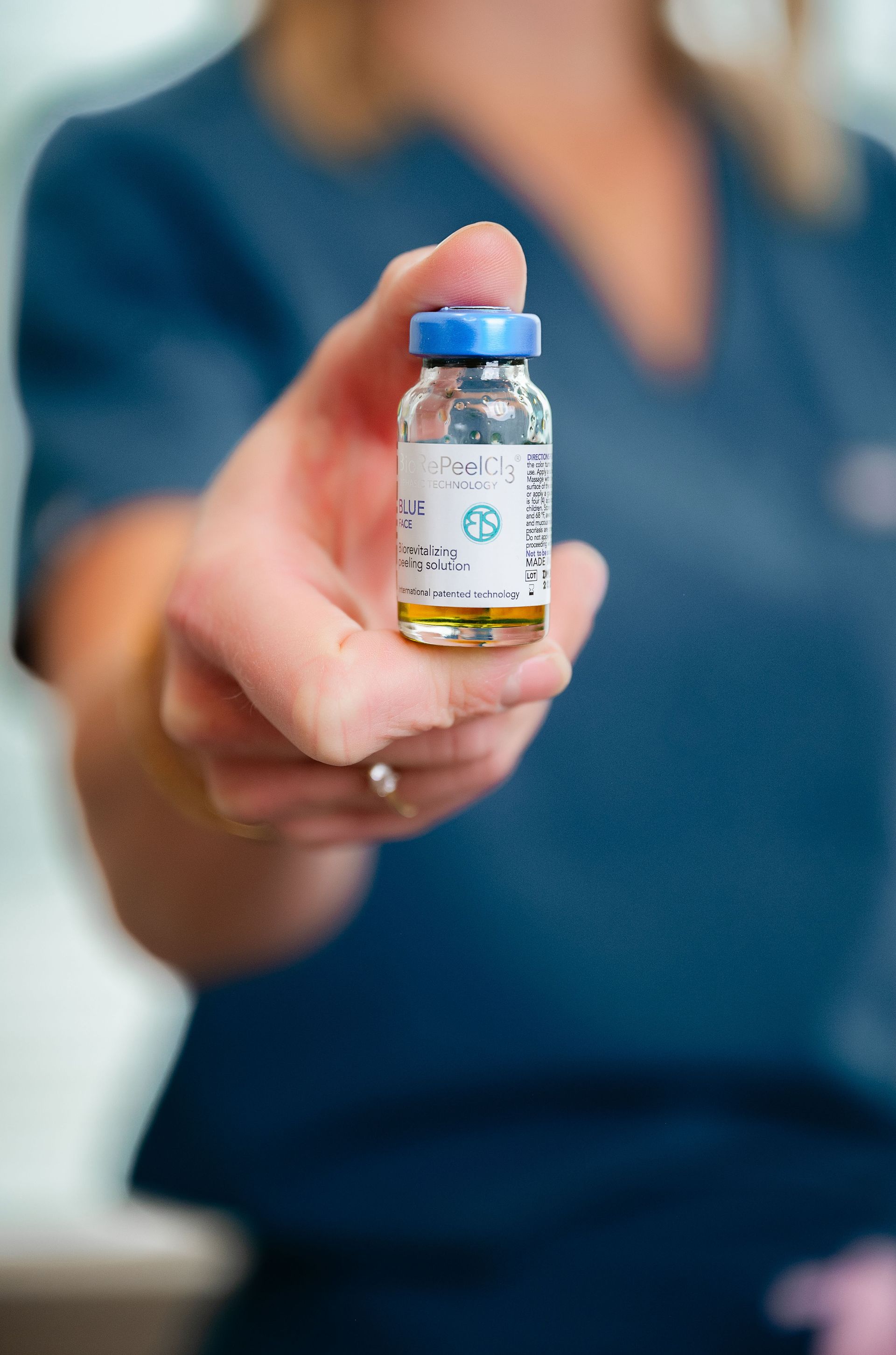a woman is holding a small bottle of medicine in her hand .