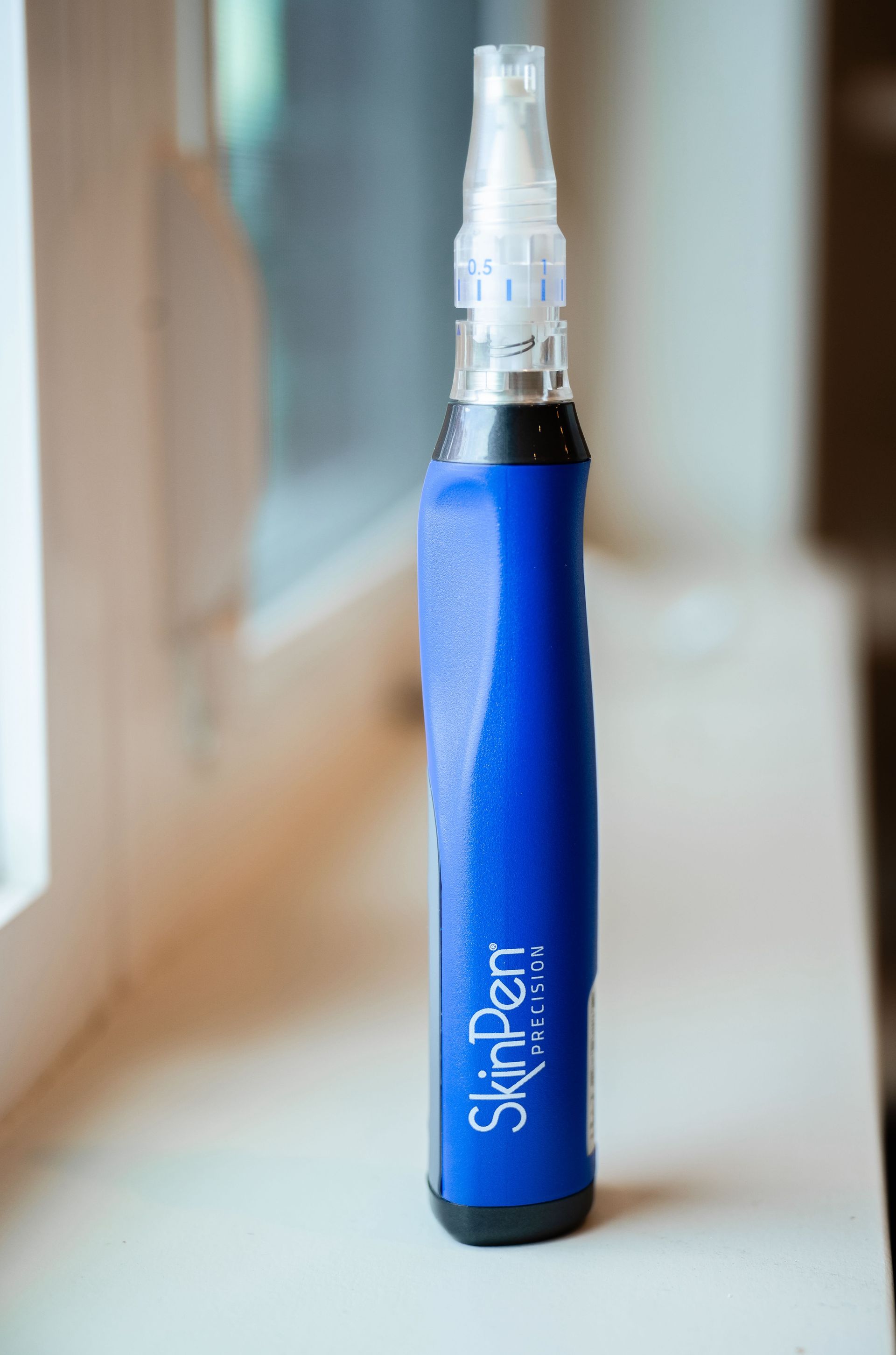 Blue skincare pen-shaped bottle standing on a windowsill