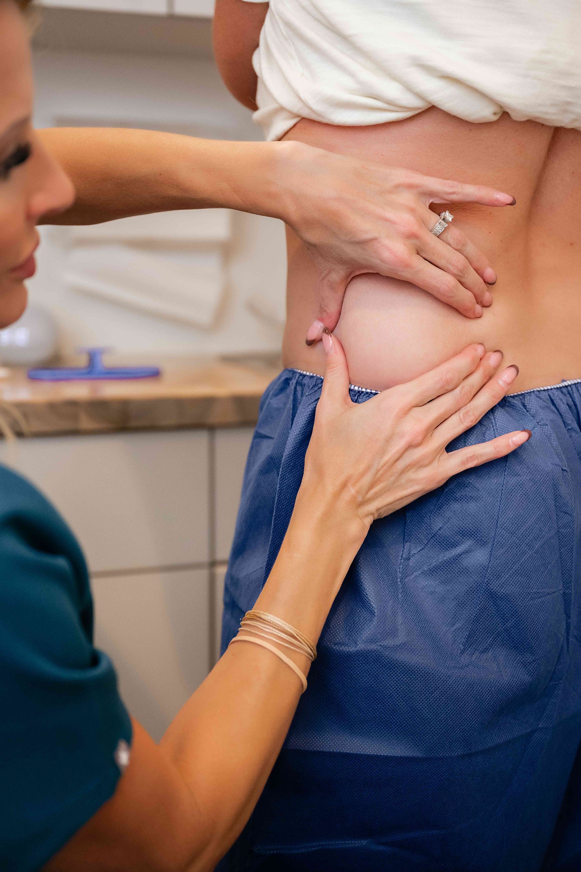 Healthcare worker examining a patient’s lower back and waist with hands in a clinical setting