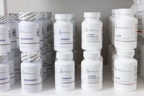 Rows of white medicine bottles with printed labels on a shelf, in a pharmacy or lab setting