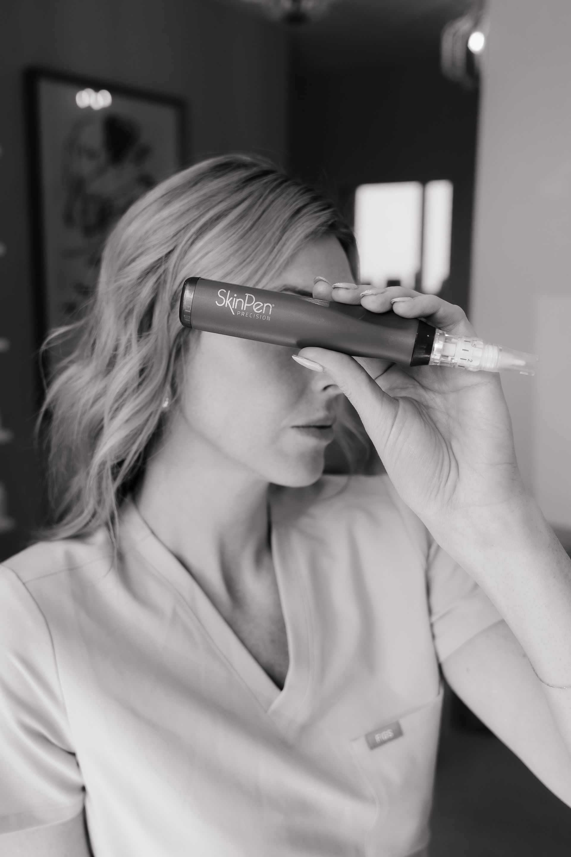 Woman holding a skincare bottle over one eye in a black-and-white portrait