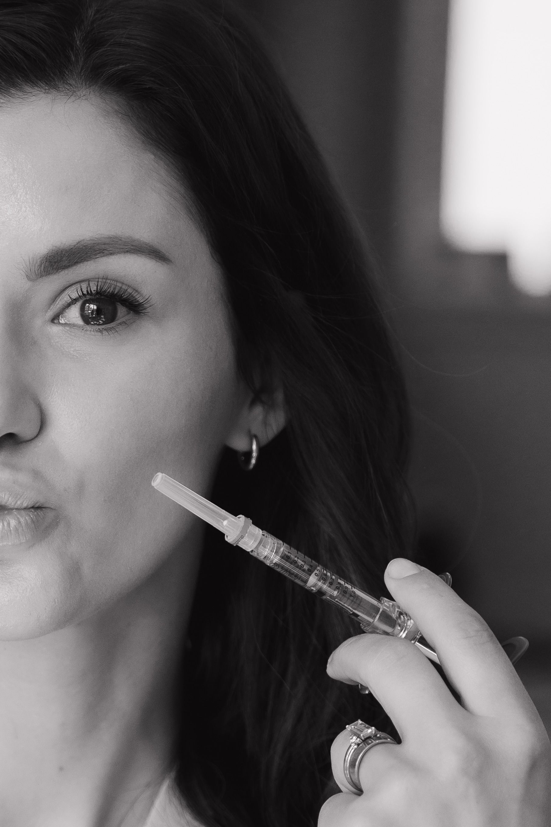 Black-and-white close-up of a woman applying lip gloss with a wand