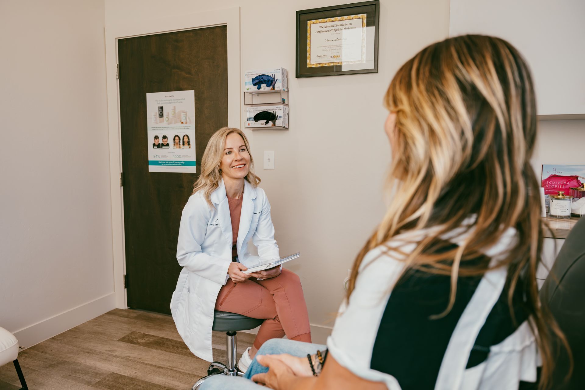 Smiling clinic staff member in teal scrubs and gloves in a dental office reception area