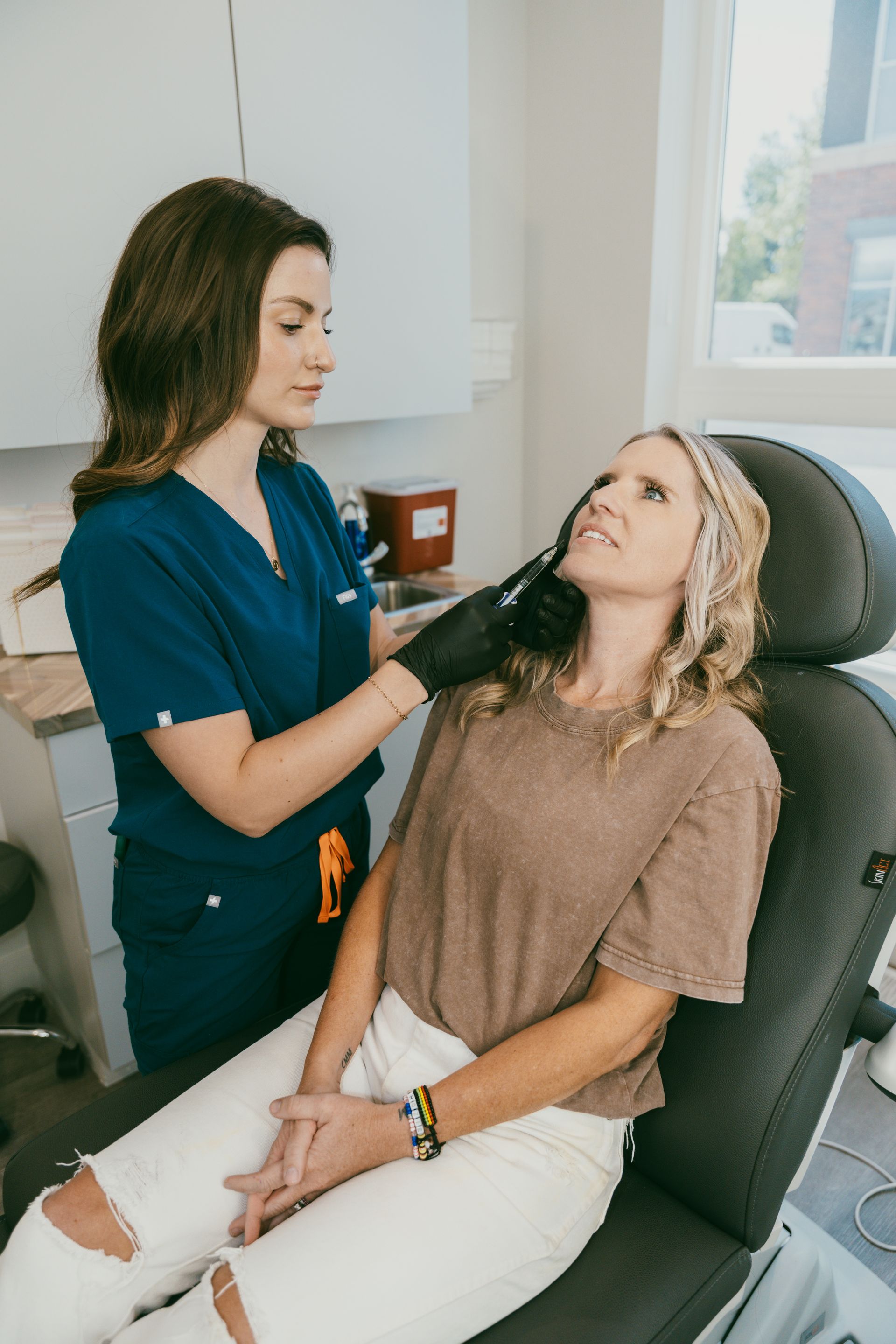 Stylist applying product to seated client in a salon chair