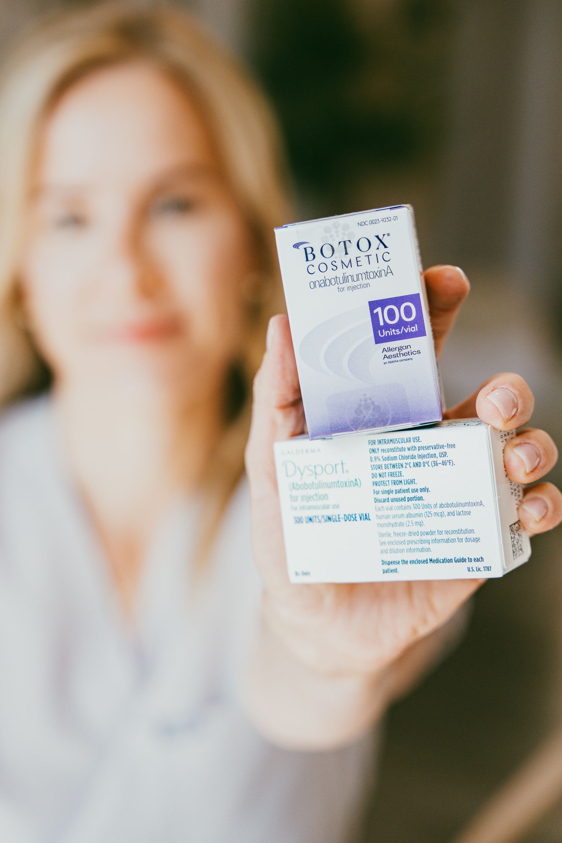 Person holding up a small white and purple product box toward the camera