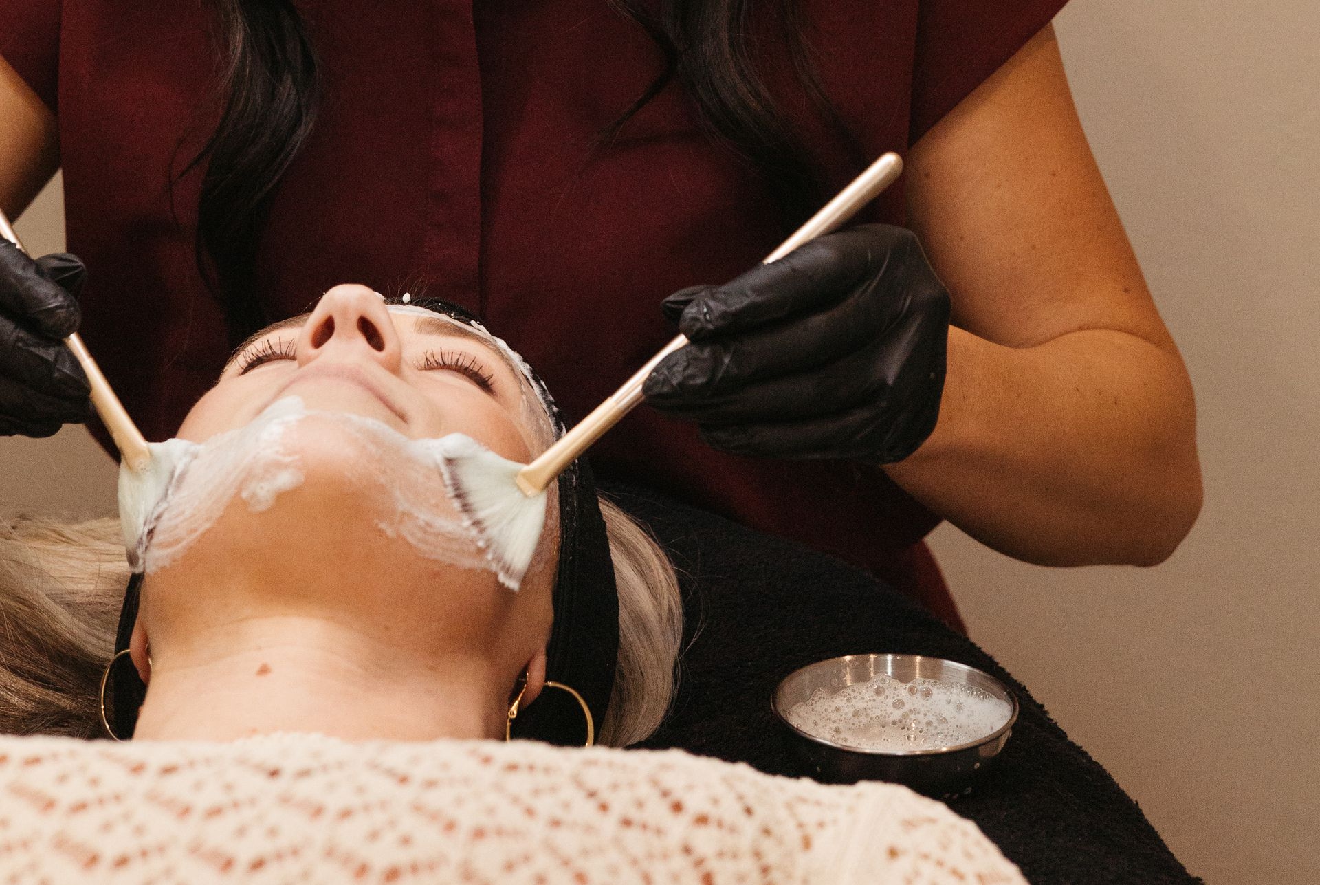 Cosmetic facial treatment with a mask being applied to a reclining client