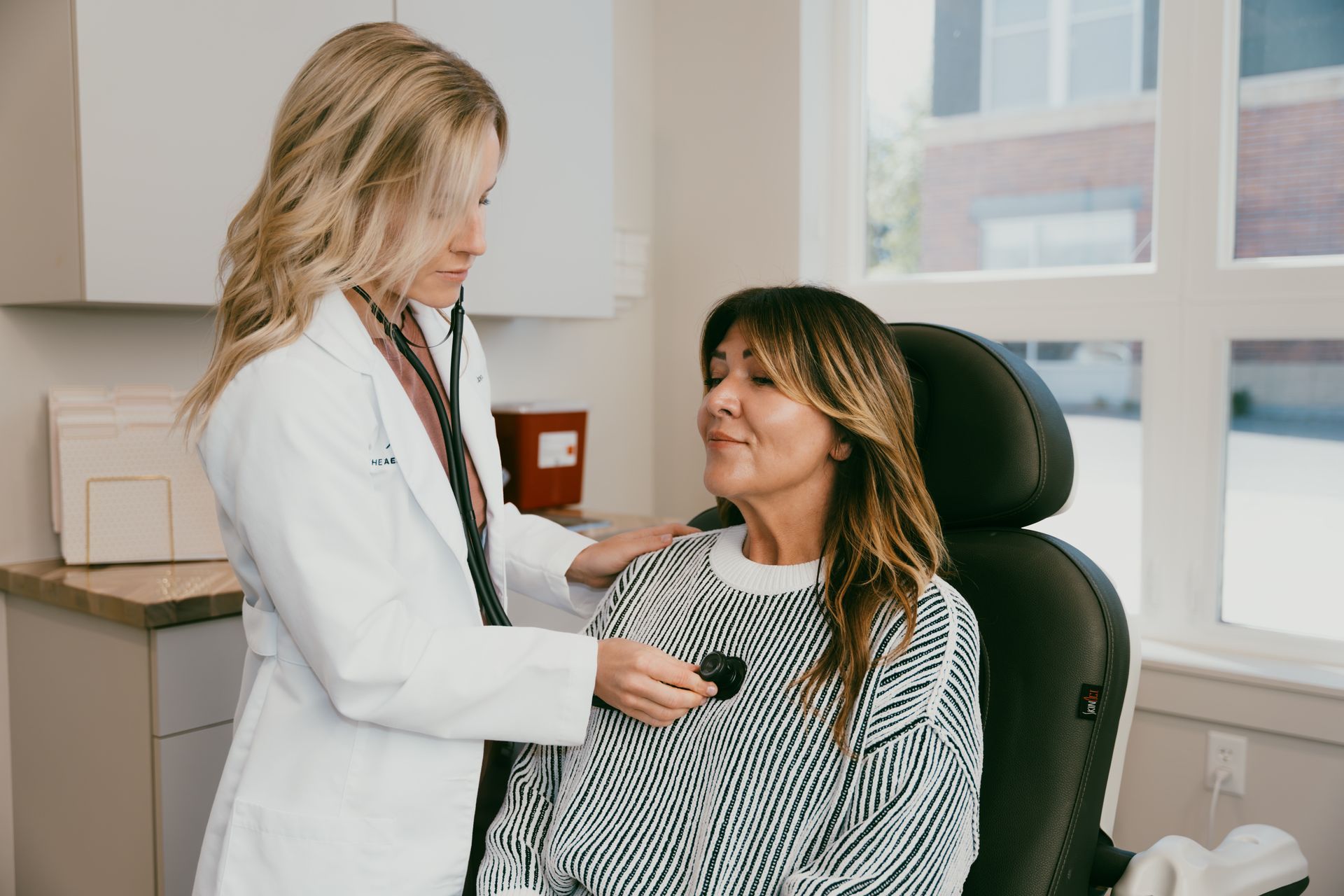 Doctor examining a seated patient in a clinic office