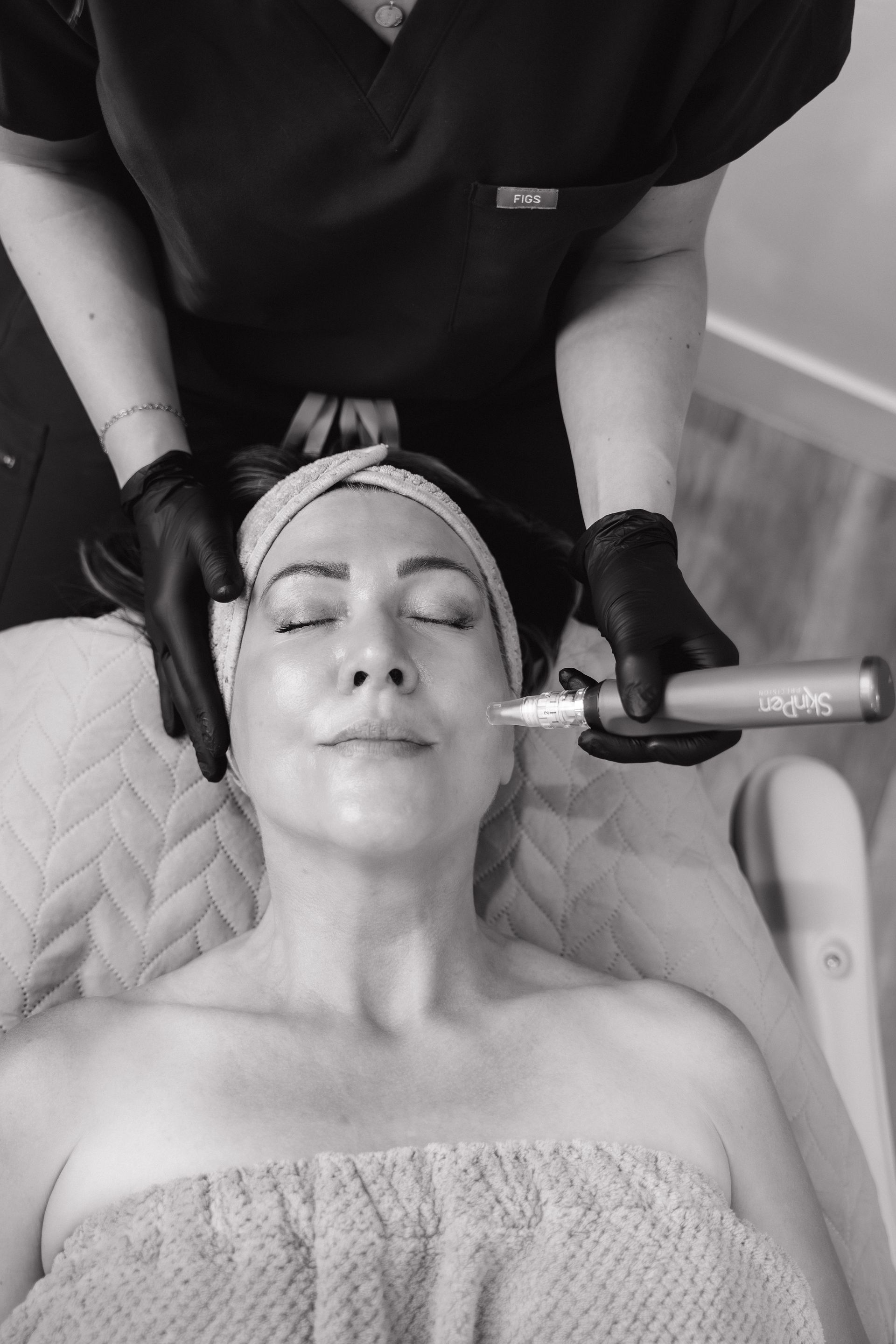 Facial treatment in progress as a practitioner applies a handheld device to a woman’s face.