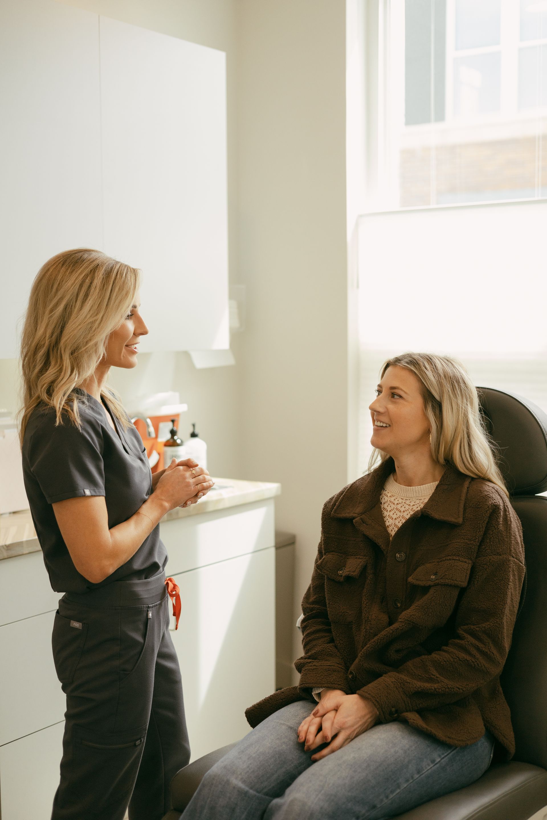 Woman consulting with a seated patient in a bright medical office