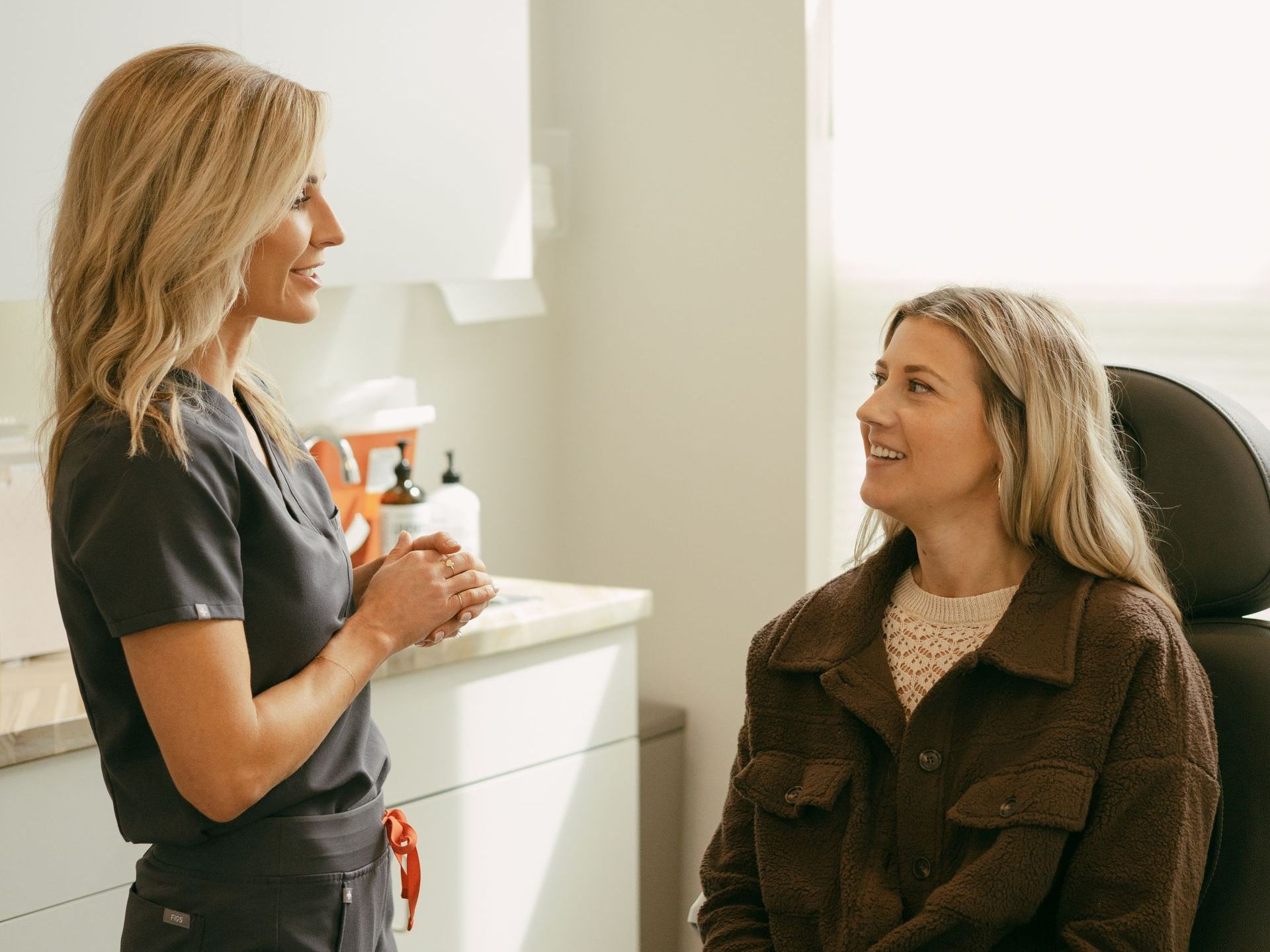 A nurse is talking to a patient who is sitting in a chair.