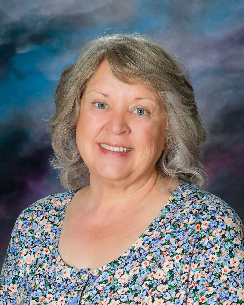A woman in a floral shirt is smiling for the camera.