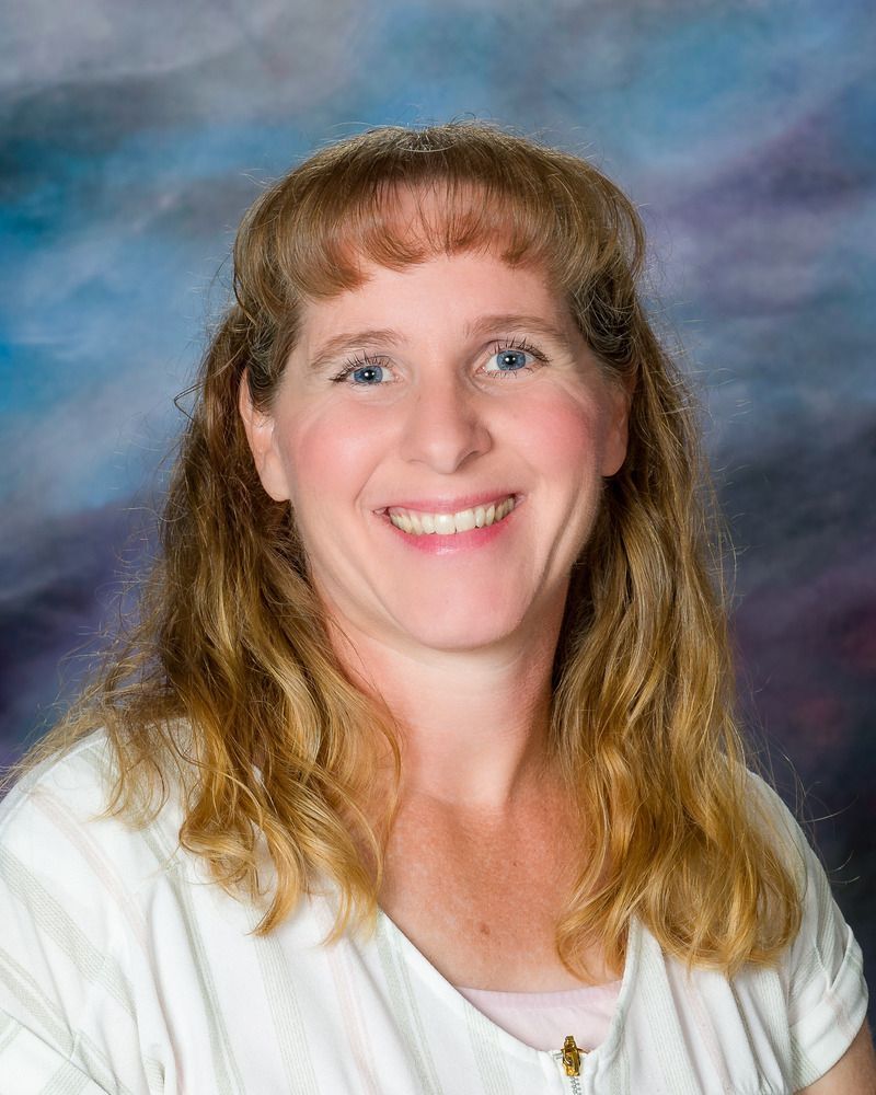 A woman in a white shirt is smiling for the camera.